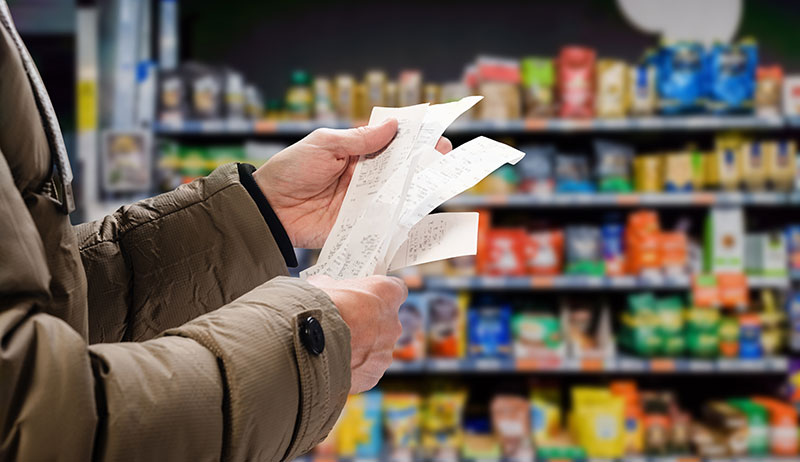 man viewing receipts in supermarket
